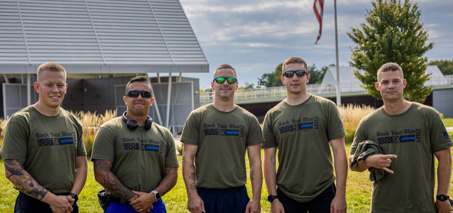 Five officers lined up in Back Your Blue 5K shirts at Big Four Station