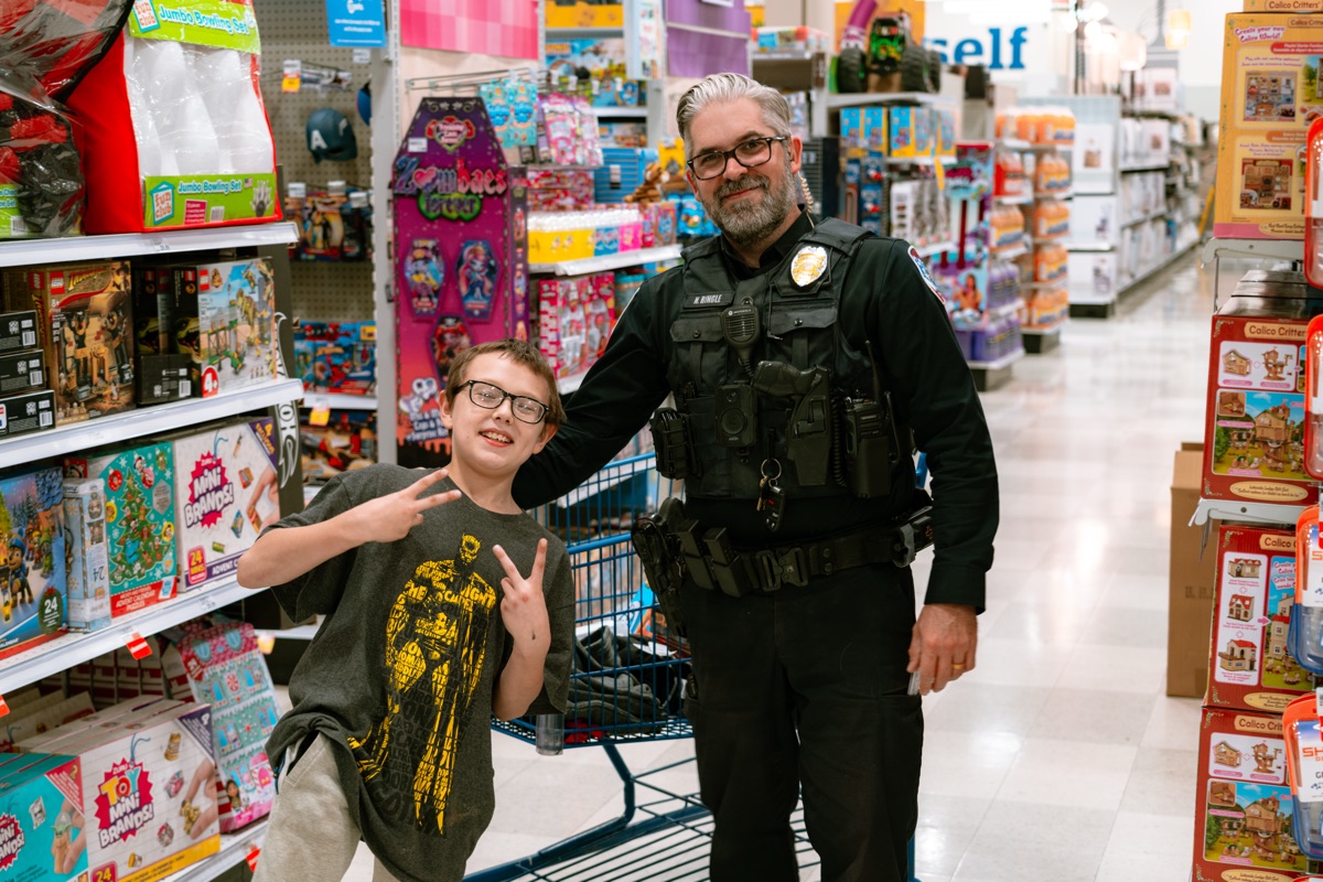 A Jeffersonville officer and a young boy flashing a peace sign in the toy aisle during Shop With A Cop